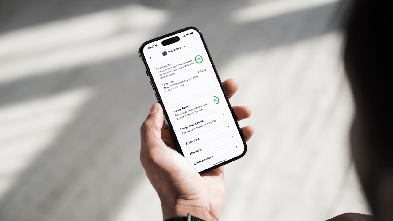 Hand hält ein Smartphone, auf dem Display die Bosch-Live-Ansicht in der App der Marke mit Akkustand, Tachostand und Tracker-Batterie